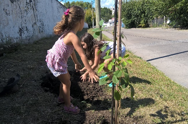 Dos niñas ayudando en la plantación de un lapacho frente al Colegio Militar